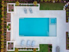 an aerial view of a swimming pool with lounge chairs around it and grass in the foreground