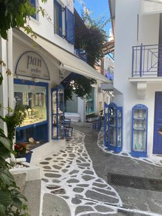 an alley way with blue and white buildings on both sides, surrounded by greenery