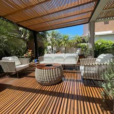 an outdoor living area with wicker furniture and wooden flooring, surrounded by palm trees