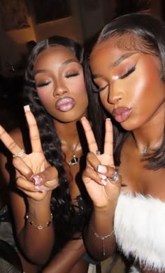 two beautiful women making the peace sign with their hands