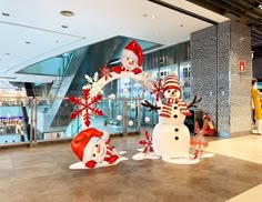 three snowmen are standing in the middle of an airport lobby with christmas decorations on them