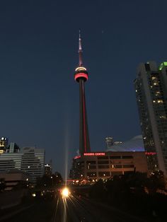 the sky tower is lit up in red and white at night, as traffic passes by