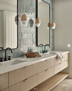 a bathroom with two sinks, mirrors and lights on the wall above them is shown