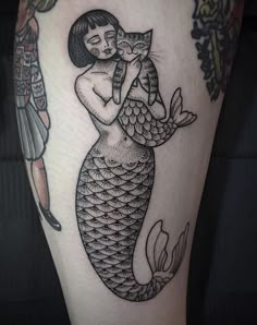 a woman holding a cat in her arms while sitting on top of a mermaid's tail