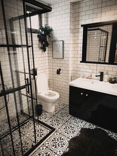 a bathroom with black and white tile flooring next to a sink, toilet and shower