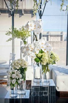 three vases with flowers are sitting on a table in front of a large window