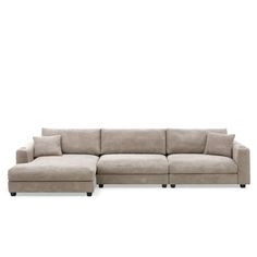 a large sectional couch with pillows on the top and bottom, sitting in front of a white