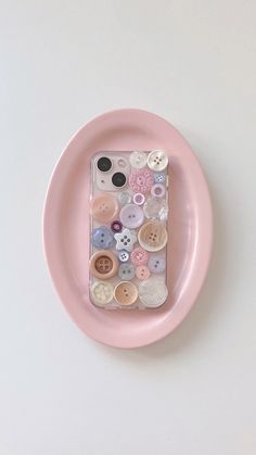 a pink plate with buttons on it and a phone case in the shape of a circle