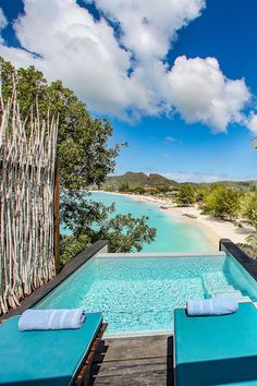 an outdoor swimming pool with chaise lounges overlooking the beach and ocean in front of it