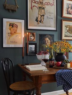 a dining room table with flowers and pictures on the wall