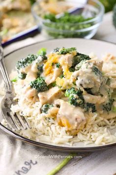 a white plate topped with rice and broccoli covered in gravy next to a fork