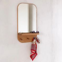 a wooden mirror hanging on the wall next to a scarf and eyeglasses in front of it