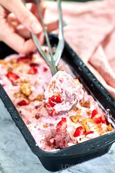 someone is scooping ice cream out of a pan with strawberries and nuts on top