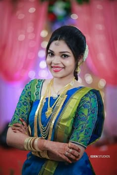 a woman in a blue and green sari posing for the camera with her arms crossed