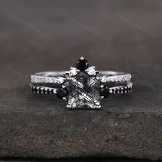 a black and white diamond engagement ring set on top of a rock with diamonds around it