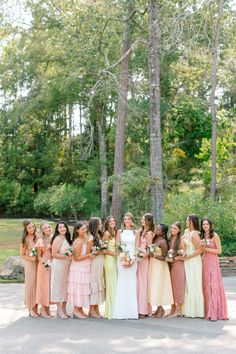 a group of women standing next to each other in front of some trees and bushes