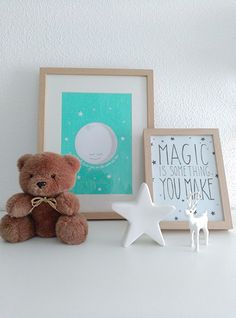 a teddy bear sitting on top of a white shelf next to a framed photograph and a star