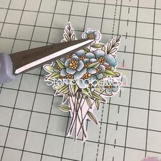 a pair of scissors sitting on top of a piece of paper next to some flowers