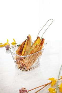 a basket filled with food sitting on top of a white counter next to yellow flowers