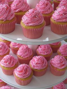 pink cupcakes are displayed on three tiered plates