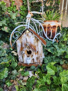 a bird house sitting on top of a pile of green leaves next to a bike