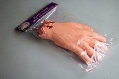 an orange plastic hand in a clear plastic bag on top of a gray countertop