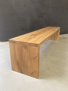 a wooden bench sitting on top of a white floor next to a gray wall in an empty room