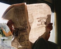 a person reading a newspaper while sitting in a chair