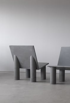 three concrete benches sitting next to each other on top of a cement floor in front of a white wall