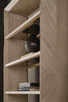 a book shelf with books and a vase on top