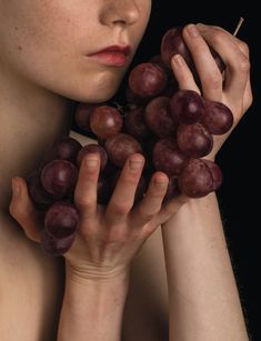 a woman holding bunches of grapes in her hands