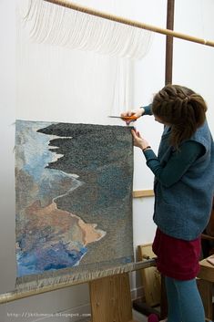 a woman is painting on a large piece of art