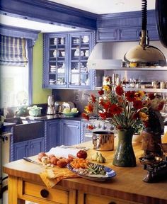 a kitchen with blue cabinets and flowers on the counter top in front of an oven