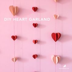 paper hearts hanging from strings on a pink background with the words diy heart garland