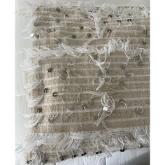 a white and beige wall hanging with fringes