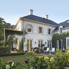 a large white house surrounded by greenery and flowers