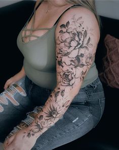 a woman sitting on top of a couch with flowers tattooed on her arm and leg