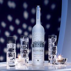 a bottle of belvede vodka on a table with glasses and ice cubes