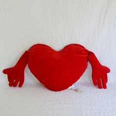 a red heart shaped stuffed animal laying on top of a bed