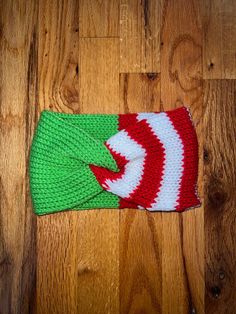 a green and red knitted hat on top of a wooden floor