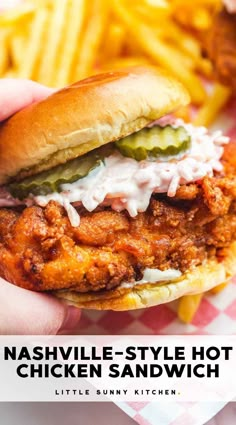 a hand holding a chicken sandwich with pickles and mayonnaise on the side