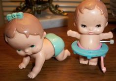 two little baby dolls sitting on top of a wooden table