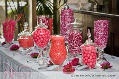 a table topped with lots of candy covered jars and vases filled with pink candies