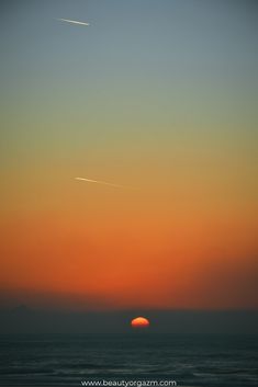 the sun is setting over the ocean with no clouds in sight as it rises above the horizon