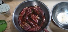 the meat is being cooked in the pan on the table next to other cooking utensils