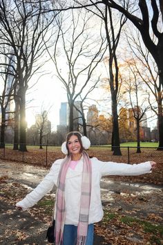 a woman is standing in the park with her arms outstretched