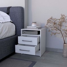 a white nightstand with three drawers next to a bed and a plant in a vase