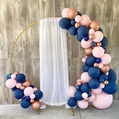 a balloon arch with blue, pink and gold balloons in the shape of an o