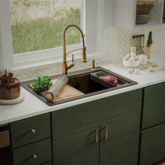 a kitchen sink sitting under a window next to a counter top with utensils