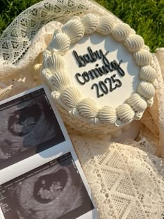 a birth announcement cake sitting on top of a lace covered table cloth next to photos